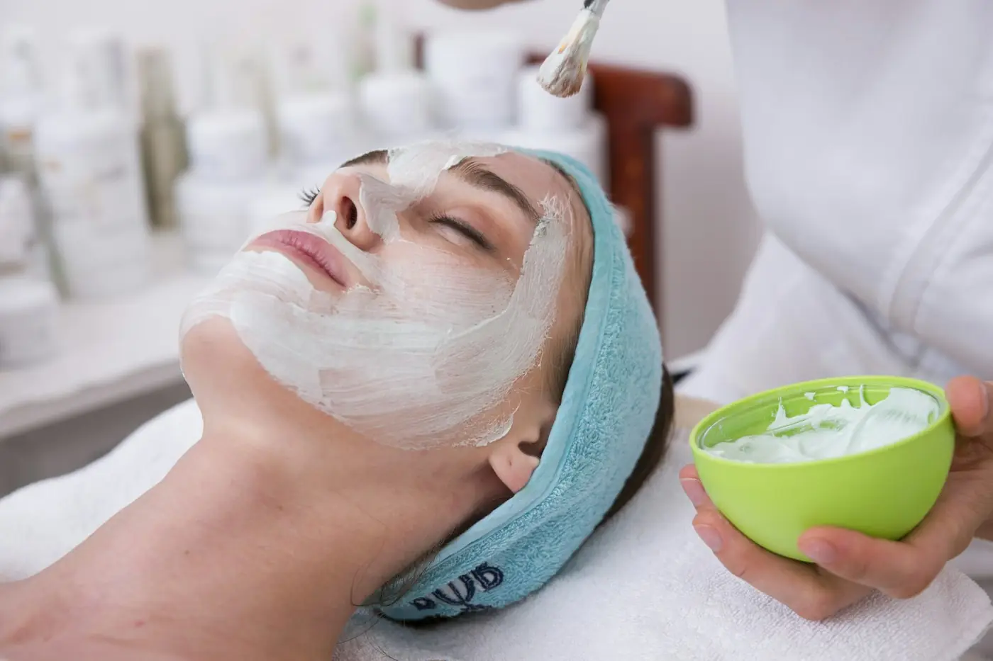 Esthetician brushing a hydrating mask onto a client's face
