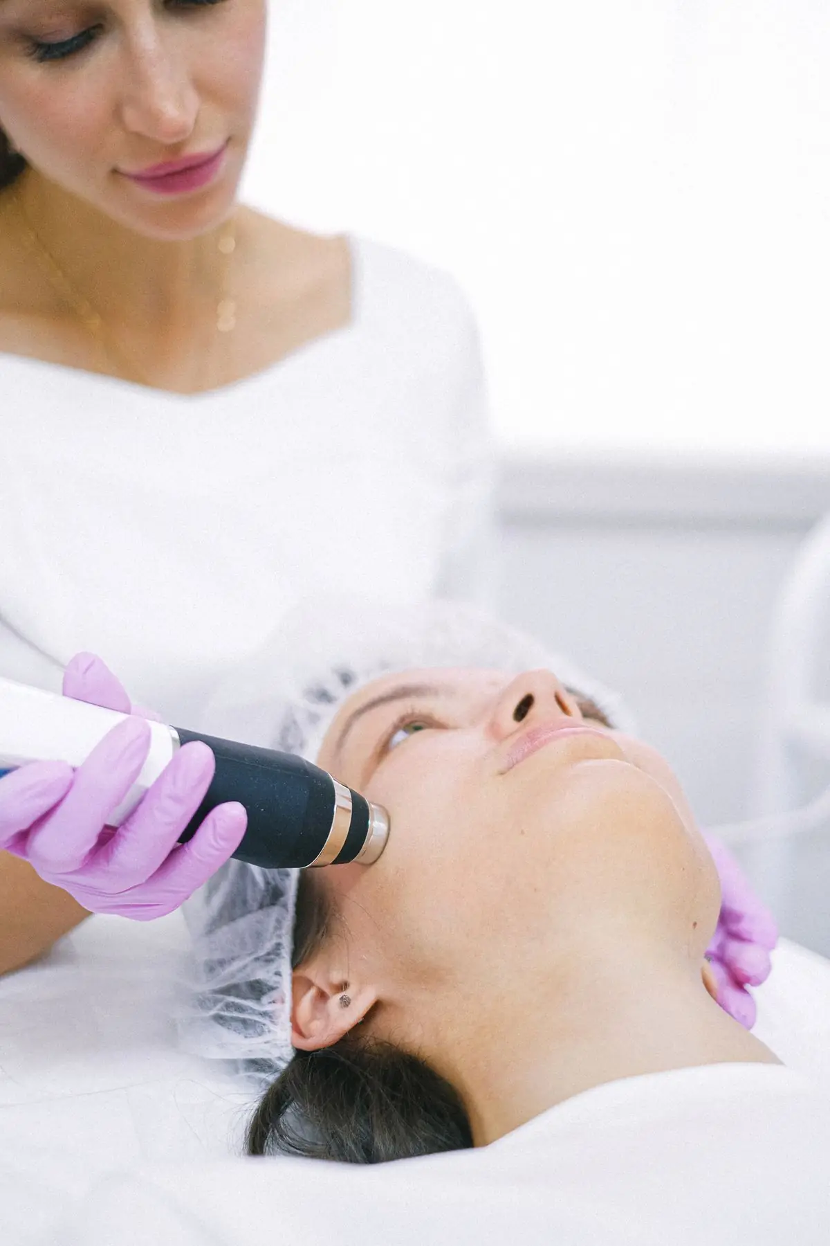Esthetician gliding a handheld skin-resurfacing wand across a client's cheek