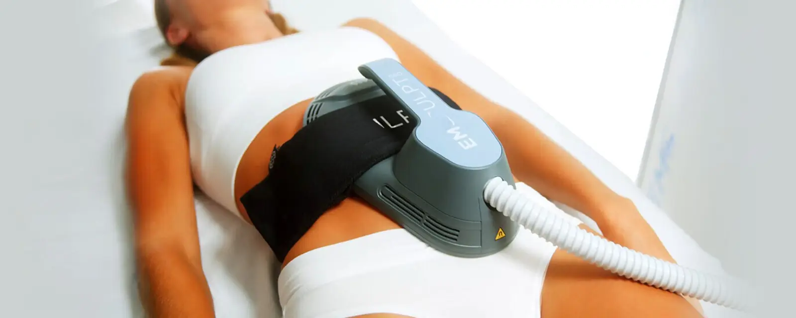 Emsculpt NEO applicator strapped over a client's abdomen during a body-contouring session